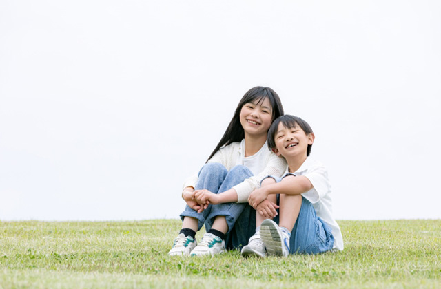 芝生の上で寄り添って座っている男の子と女の子