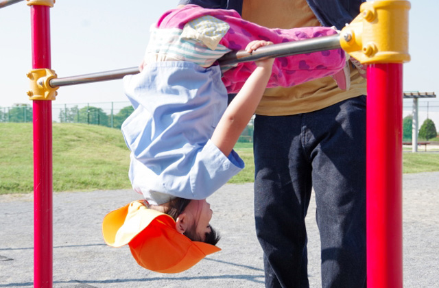 逆上がりしている子どもとサポートしている親