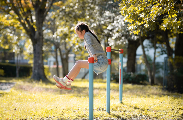 公園の鉄棒で遊んでいる女の子